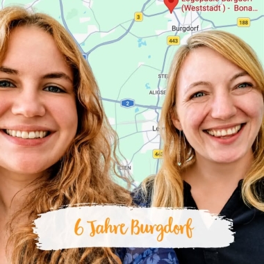 Zwei Frauen vor einer Karte lachen.