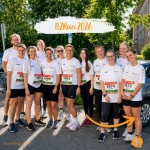 Eine Gruppe von Menschen in Sportbekleidung steht vor einem Auto.
